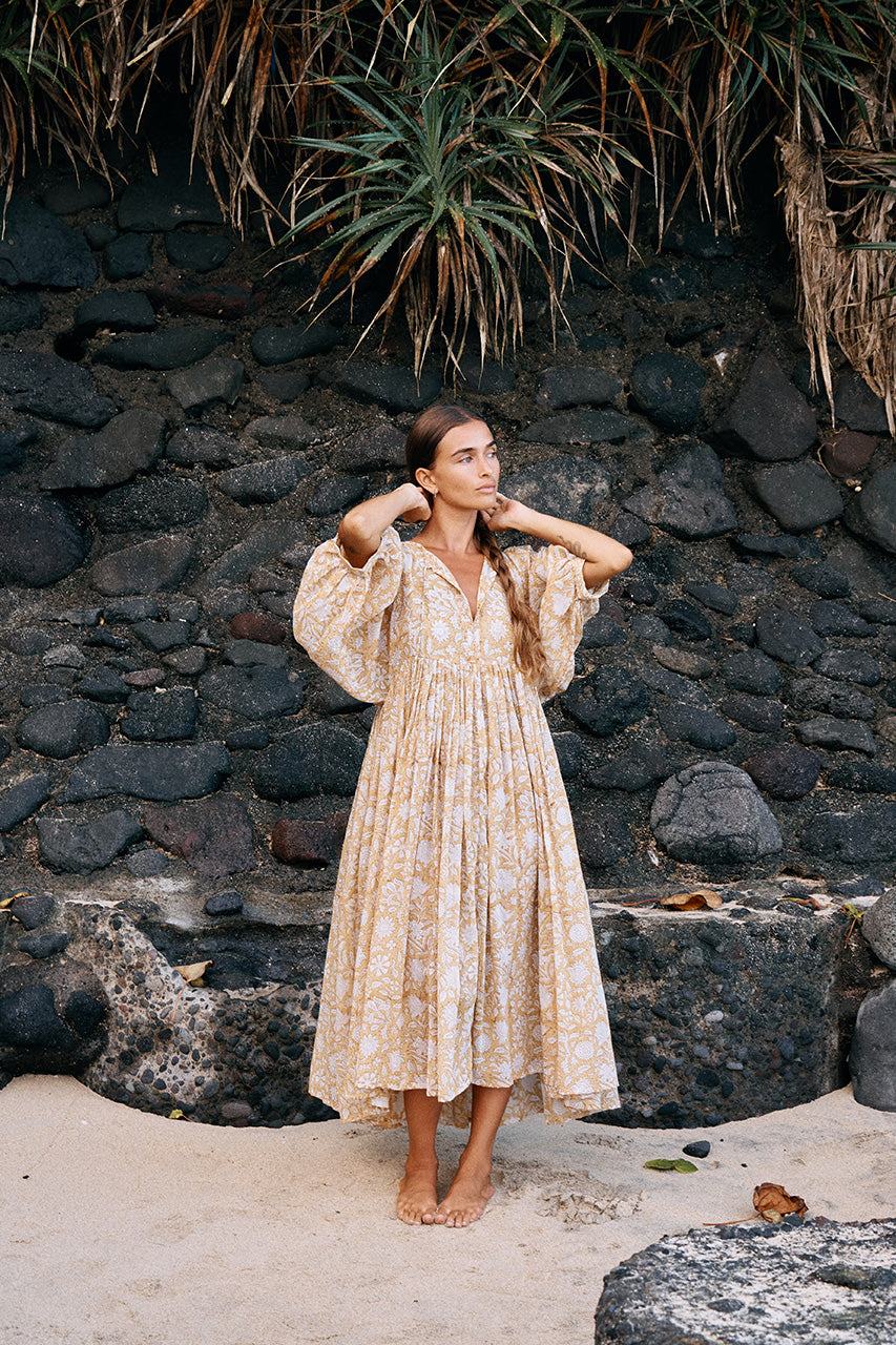 Daughters of India Kyra Midi Dress in Cumin — full length on rocky beach by volcanic wall, hand screen print cotton