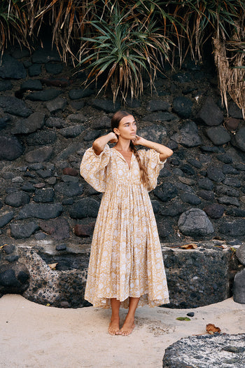 Daughters of India Kyra Midi Dress in Cumin — full length on rocky beach by volcanic wall, hand screen print cotton