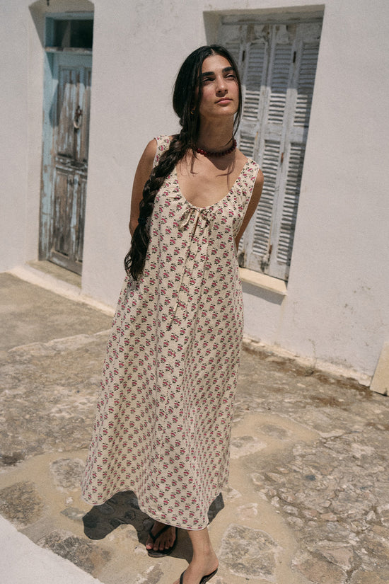 Woman standing on a stone path in a Greek whitewashed setting wearing the Daughters of India Sundress Midi in Peony, full-length front view with braided hair